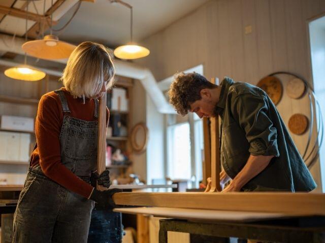 Two people working on a woodworking project in a workshop as part of a DIY home improvement task