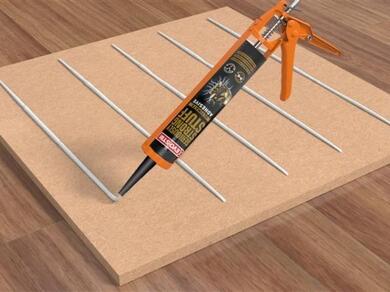 Applying grab adhesive in beads to a wooden panel using a caulking gun for installation and bonding