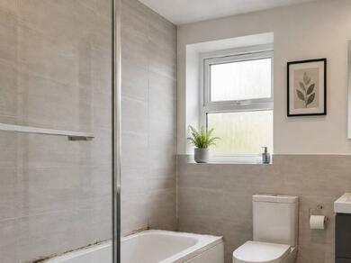 Bathroom with a bathtub and tiled walls showing worn and discolored silicone sealant that needs replacing to restore a clean waterproof seal.