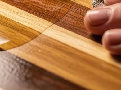 Close-up of dried wood glue being removed from a wooden surface during a woodworking project.