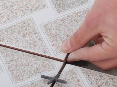 Floor tiles being positioned with tile spacers to create even grout lines during a floor tiling project.